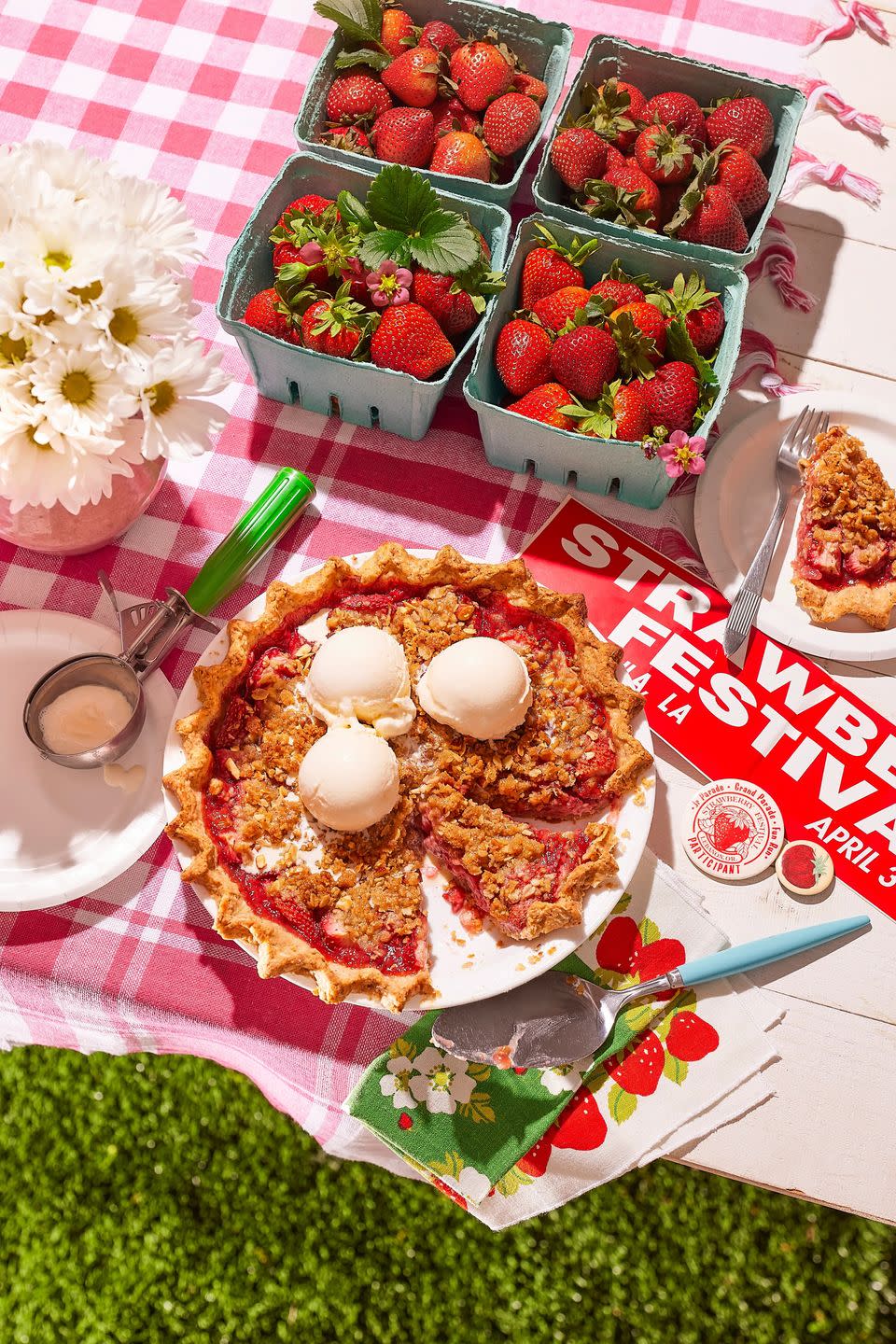 strawberry almond crumble pie on a table with ice cream on top and strawberry festival bumper stickers