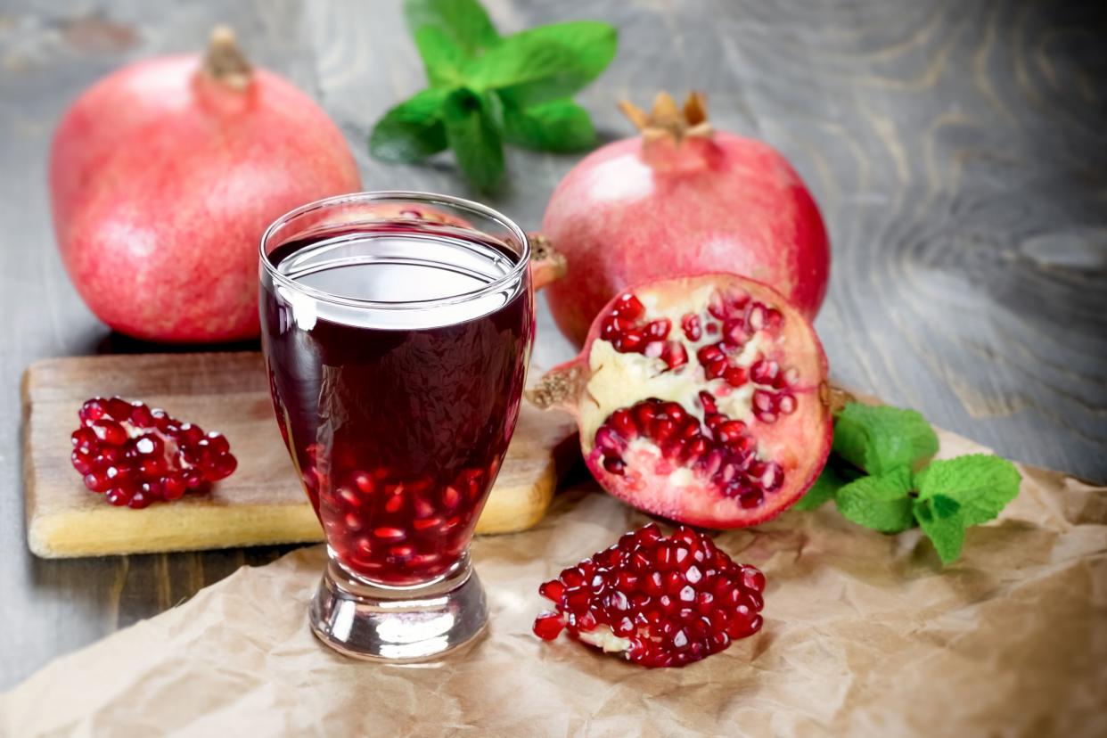 Refreshing and healthy pomegranate juice and pomegranate fruit on table