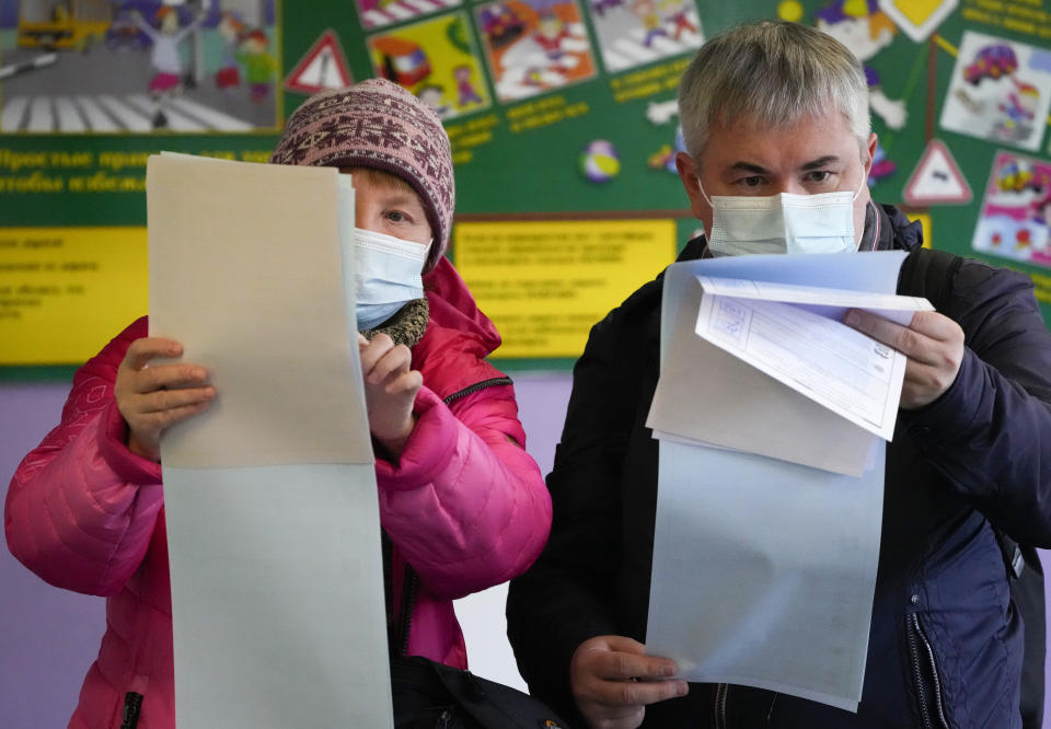 People examine their ballots during the State Duma, the Lower House of the Russian Parliament and local parliament elections at a polling station in St. Petersburg, Russia, Sunday, Sept. 19, 2021. The head of Russia's Communist Party, the country's second-largest political party, is alleging widespread violations in the election for a new national parliament in which his party is widely expected to gain seats. (AP Photo/Dmitri Lovetsky)