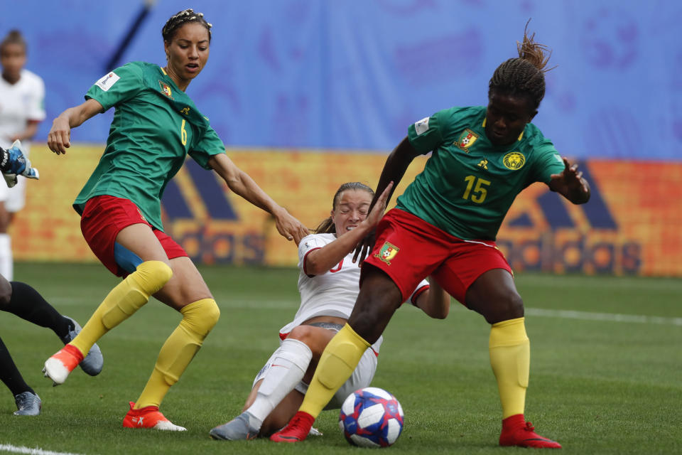 England's Fran Kirby, center, falls as in action with Cameroon's Estelle Johnson, left, and Cameroon's Ysis Sonkeng during the Women's World Cup round of 16 soccer match between England and Cameroon at the Stade du Hainaut stadium in Valenciennes, France, Sunday, June 23, 2019. (AP Photo/Michel Spingler)