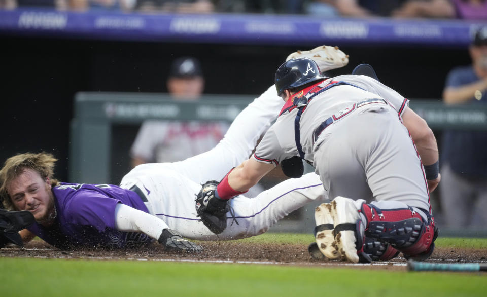 Colorado Rockies' Hunter Goodman, left, avoids the tag by Atlanta Braves catcher Sean Murphy to score during the second inning of a baseball game Tuesday, Aug. 29, 2023, in Denver. (AP Photo/David Zalubowski)