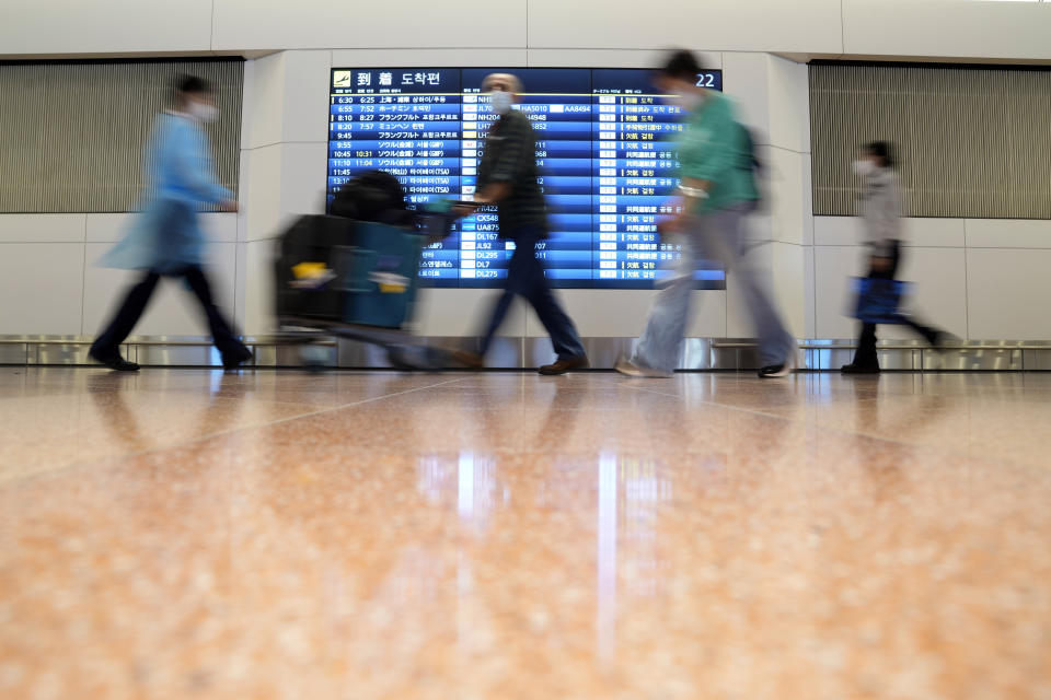 Foreign traveller and airport staff walk at the Haneda International Airport Tuesday, Oct. 11, 2022, in Tokyo. Japan's strict border restrictions are eased, allowing tourists to easily enter for the first time since the start of the COVID-19 pandemic. Independent tourists are again welcomed, not just those traveling with authorized groups. (AP Photo/Eugene Hoshiko)