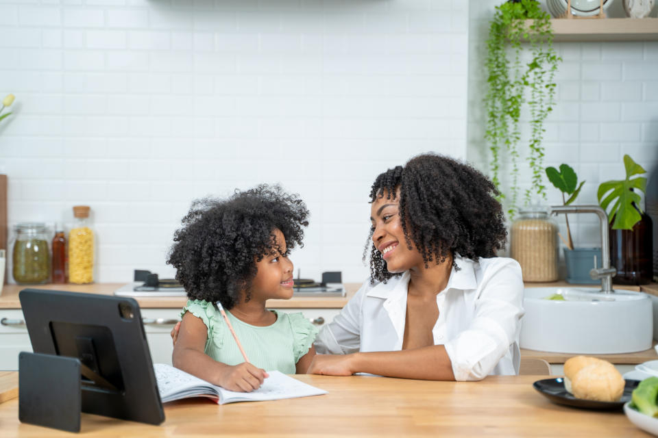 Woman and child happily engaging over a book in a kitchen setting