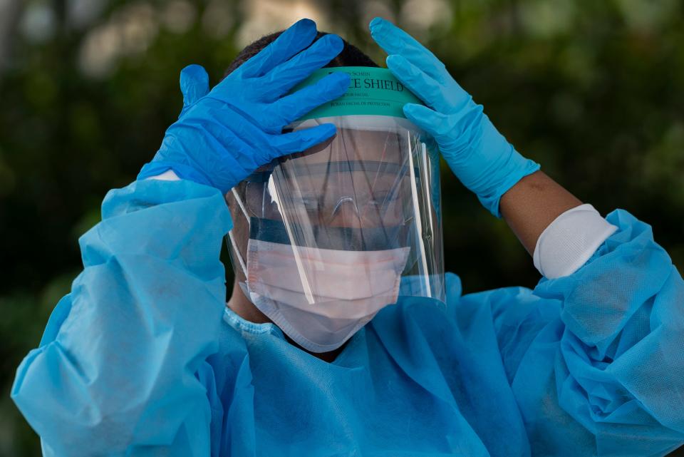 Healthcare worker Ludnie Emile prepares to test people for COVID-19 at their drive-thru coronavirus testing station in Palm Springs, Fla. on March 19, 2020.