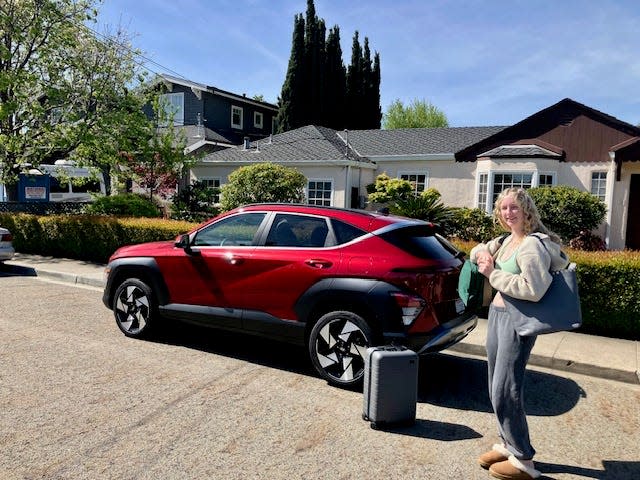 A passenger holding bags waits to get into the 2024 Hyundai Kona Limited AWD