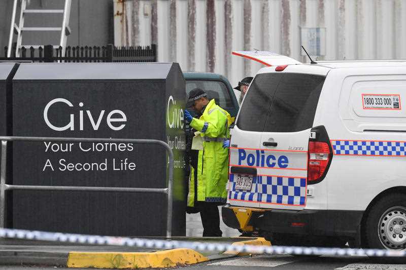 A police van is parked as officers look at a charity bin, where a woman's body was found, near a Burleigh Heads shopping centre.