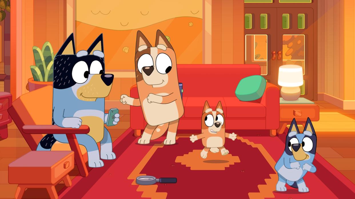 Bluey characters Bandit, Chilli, Bingo and Bluey are shown in a living room.