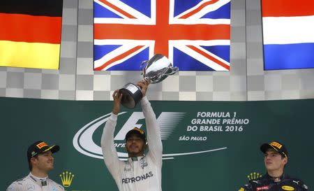 Formula One - F1 - Brazilian Grand Prix - Circuit of Interlagos, Sao Paulo, Brazil - 13/11/2016 - Mercedes' Lewis Hamilton of Britain raises his trophy during the victory ceremony after winning the race as second placed finisher and teammate Nico Rosberg of Germany (L) and third placed finisher Red Bull's Max Verstappen of the Netherlands look on. REUTERS/Nacho Doce