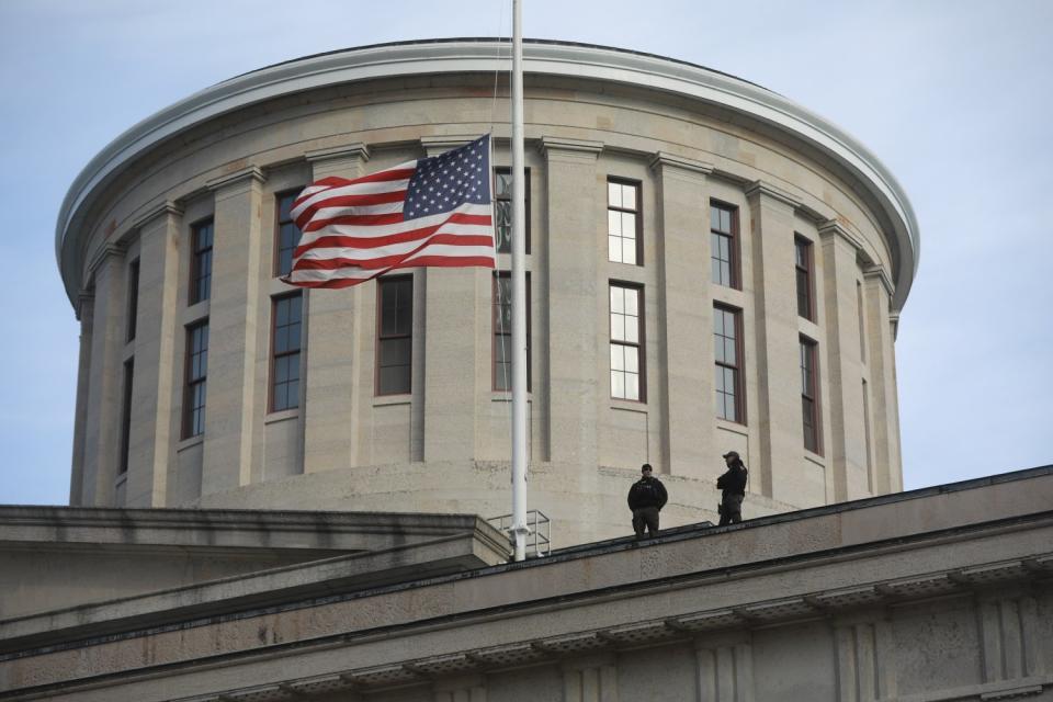 Two Ohio State Highway Patrol troopers look out from the Ohio Statehouse roof in Columbus.