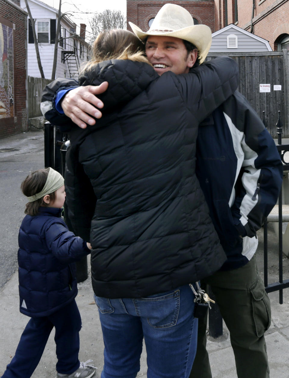 In this Tuesday, March 25, 2014 photo, Carlos Arredondo embraces a family friend while walking along Centre Street in the Jamaica Plain neighborhood of Boston. Arredondo, along with volunteer Devin Wang and EMT Paul Mitchell, are credited with helping to save the life of Jeff Bauman, who suffered traumatic injuries in the Boston Marathon bombings. (AP Photo/Charles Krupa)