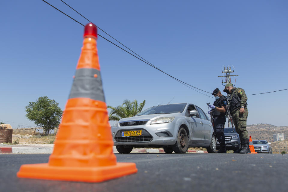 A Palestinian security unit mans a checkpoint at an entrance of in the West Bank city of Ramallah, Thursday, July 2, 2020. The Palestinian Authority has announced a five-day total lockdown in the West Bank starting Friday, in response to a major increase in coronavirus cases and deaths in recent days. (AP Photo/Nasser Nasser)