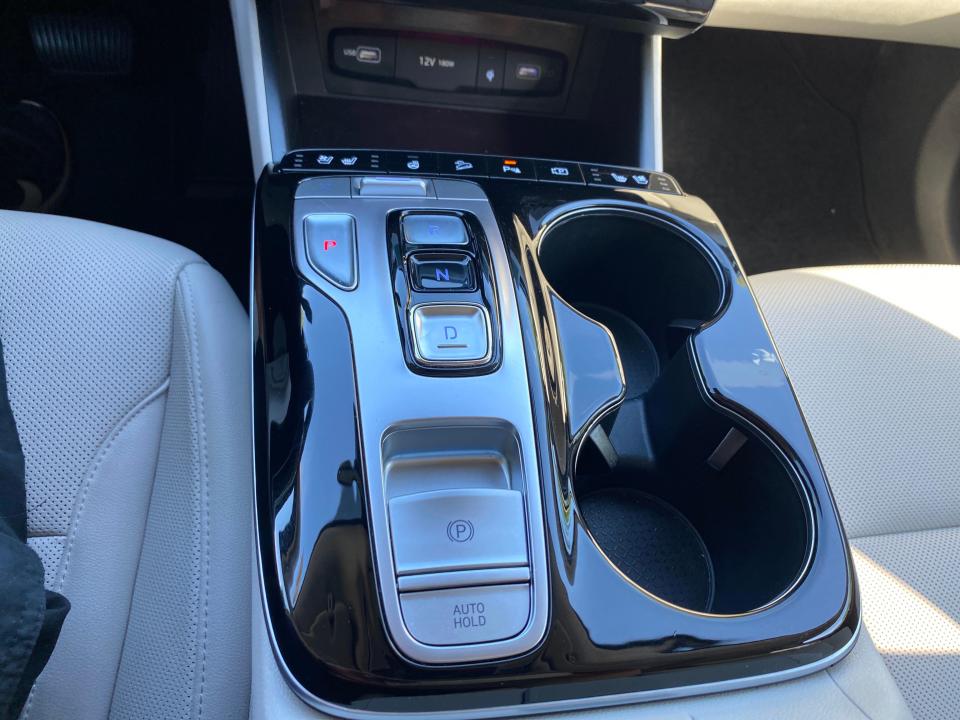 A 2024 Hyundai Tucson Hybrid center console's push-button shifter and cup holders.