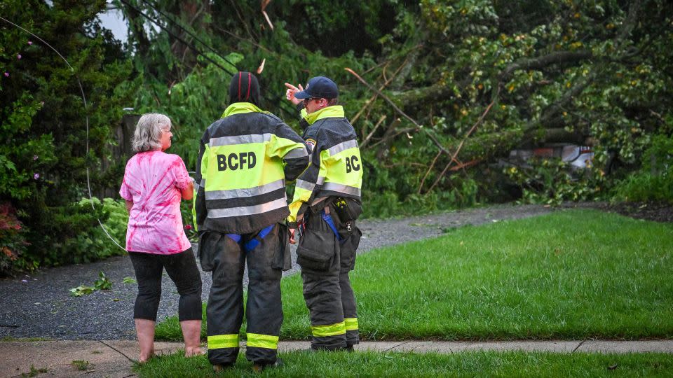 Baltimore County firefighters speak with a resident after several trees took out the power lines and fell on her daughter's car in Towson, Maryland, on Monday. - Jerry Jackson/The Baltimore Sun/AP