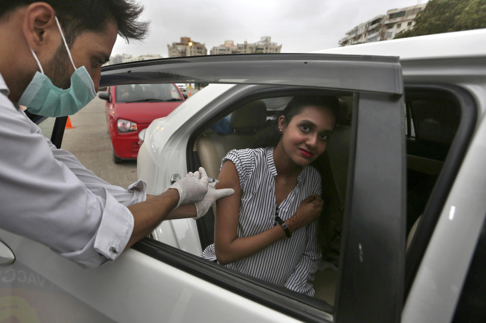 A woman receives the Sinovac COVID-19 vaccine from a health worker at a drive-through vaccination center, in Karachi, Pakistan, Saturday, July 31, 2021. (AP Photo/Fareed Khan)