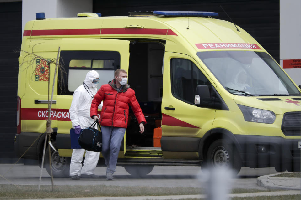 A medical worker helps a man, suspected of having the coronavirus infection, to get out from an ambulance at a hospital outside Moscow, Russia, Friday, March 20, 2020. The Russian government says that it has decided to bar entry to all foreigners starting Wednesday. For most people, the new coronavirus causes only mild or moderate symptoms, such as fever and cough. For some, especially older adults and people with existing health problems, it can cause more severe illness, including pneumonia. (AP Photo/Pavel Golovkin)