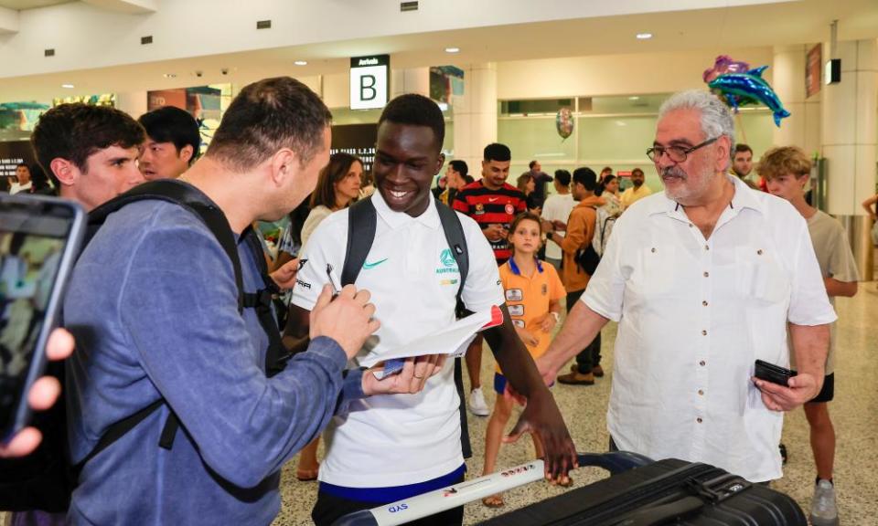 Garang Kuol of the Socceroos signs autographs at Sydney airport.