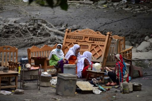 A Pakistani Kashmiri family gather around their belongings outside their damaged house following heavy monsoon rains in Neelum valley, near the Line of Control in Pakistan-controlled Kashmir