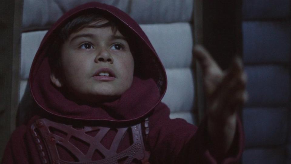 A young Din Djarin as a boy in a hood reaches out his hand in a flashback on The Mandalorian