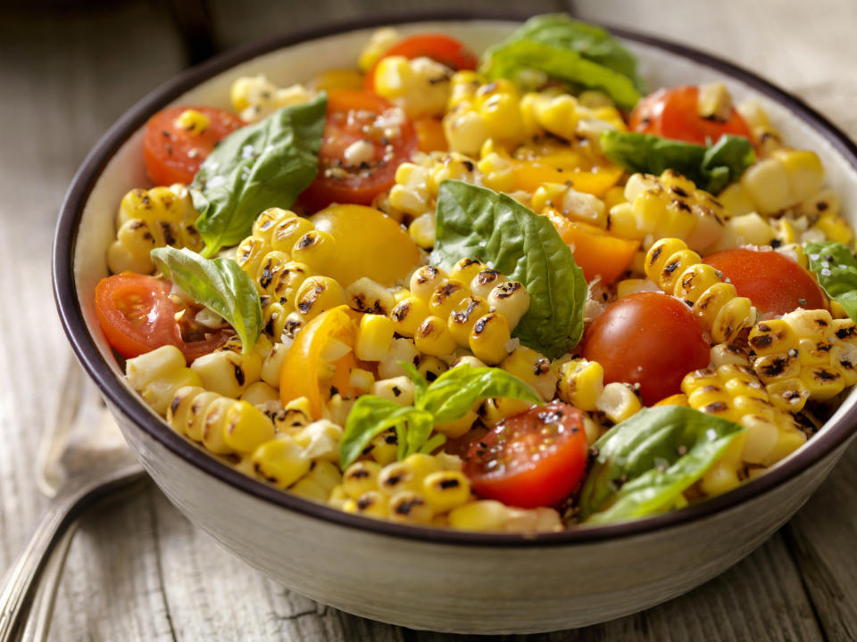 A bowl of grilled corn salad with tomatoes and basil