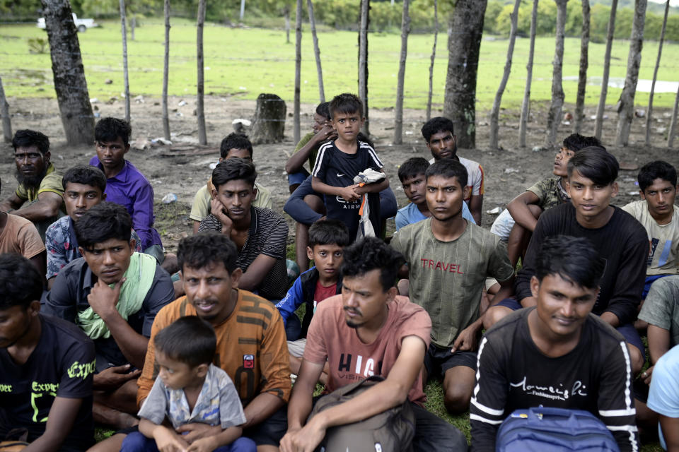 Ethnic Rohingya men sit on a beach after they land in Aceh Besar, Aceh province, Indonesia, Sunday, Dec. 10, 2023. Two boats carrying hundreds of Rohingya Muslims, including women and children, arrived at Indonesia's northernmost province of Aceh on Sunday morning after being adrift for weeks. (AP Photo/Reza Saifullah)