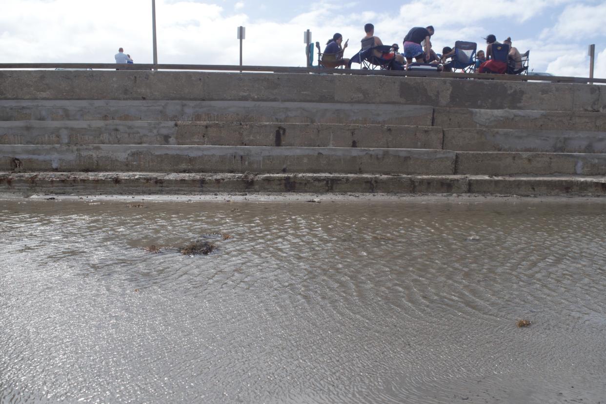 A family visits Michael J. Ellis Beach and Seawall on North Padre Island as water pools up to the edge of the wall on the afternoon of June 18, 2024.