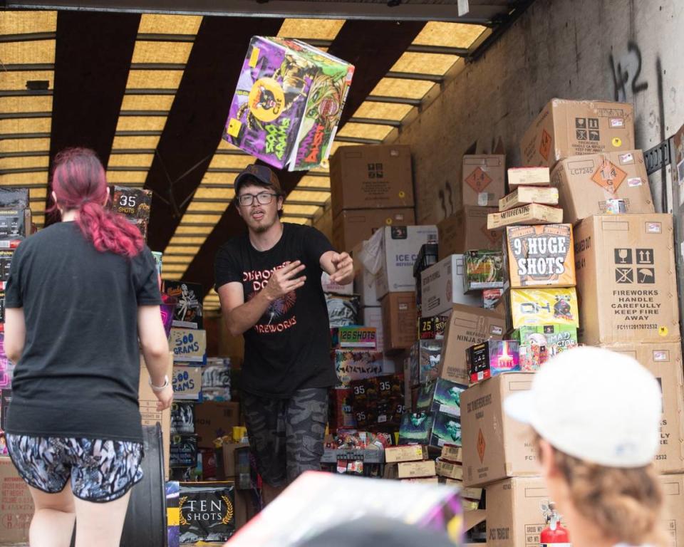 Boxes of fireworks are tossed out of a storage trailer by helpers as Dishonest Don’s fireworks prepares to open for business on Wednesday, July 3, 2024, after their tent collapsed on Tuesday night.