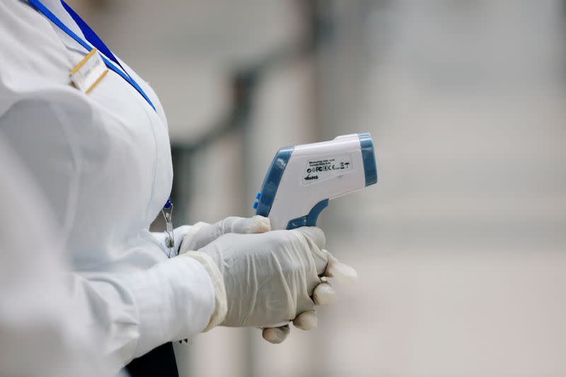 A health worker holds a thermometer as she waits to screen travellers for signs of the coronavirus at the Kotoka International Airport in Accra