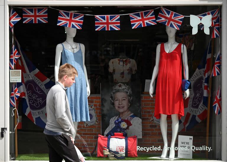 Un joven pasa por delante de una vidriera adornada con banderines con el tema de la bandera de la Unión y un retrato de la reina Isabel II, en Colchester, este de Inglaterra, el 31 de mayo de 2022