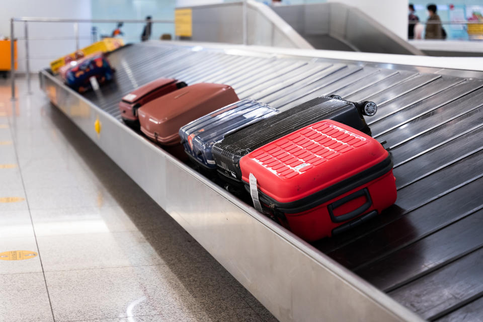 Five suitcases are on an airport baggage carousel