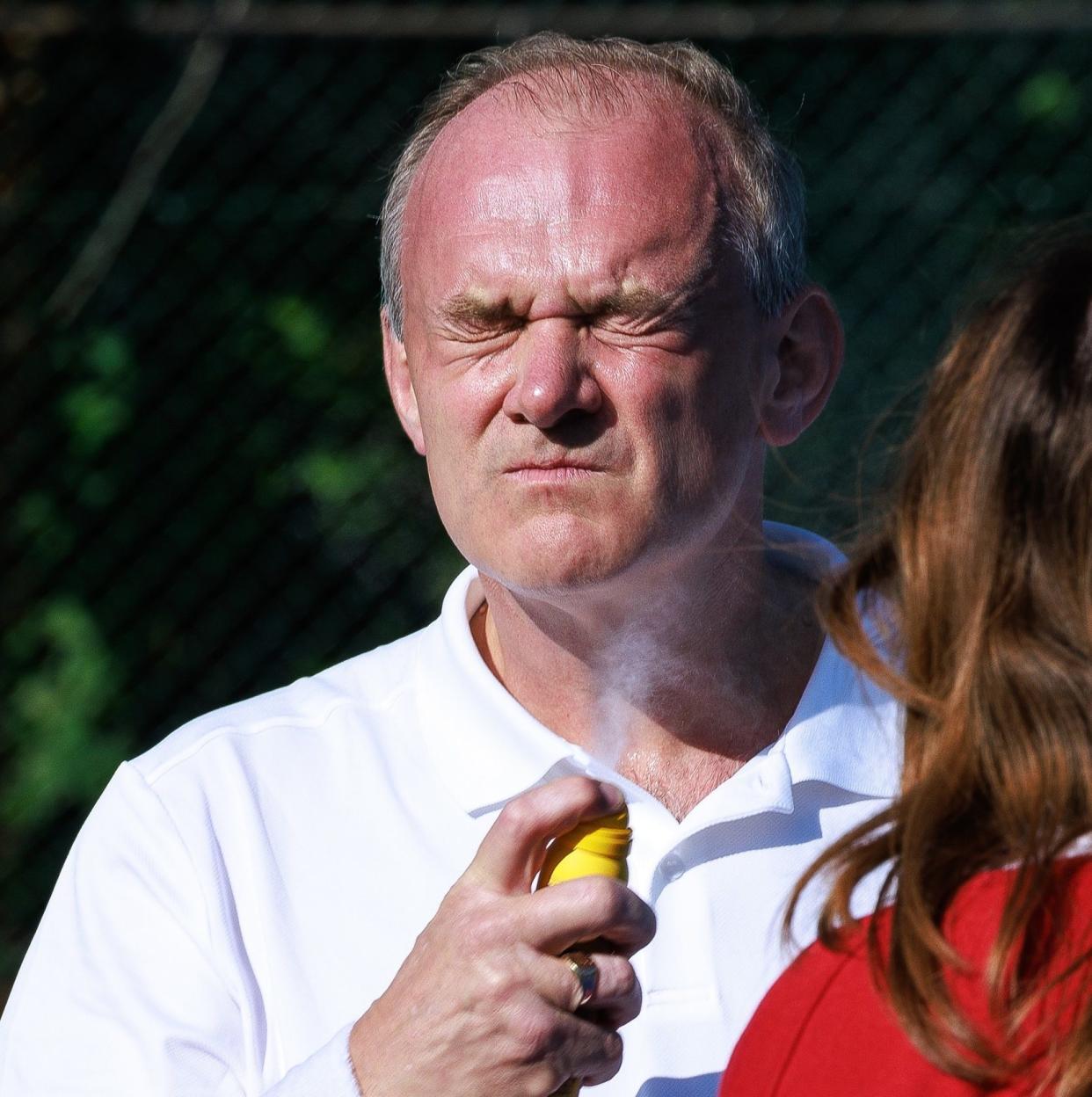 Sir Ed Davey stops to spray sunscreen as he plays tennis in Brighton