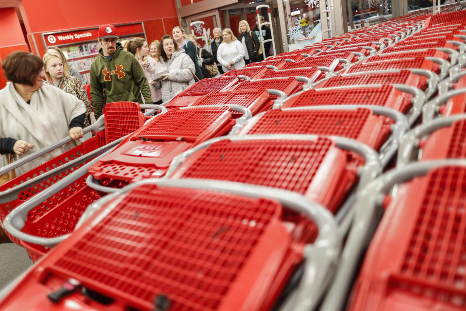 FILE - In this Nov. 23, 2018, file photo shoppers enter and take their shopping carts during a Black Friday sale at a Target store in Newport, Ky. Target is launching a private food label next month as it attempts to energize grocery sales. On Sept. 15, 2019, 650 products will appear on store shelves under the brand “Good & Gather.” (AP Photo/John Minchillo, File)