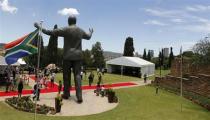 People stand near the 9-metre (30-feet) bronze statue of the late former South African President Nelson Mandela as it is unveiled as part of the Day of Reconciliation Celebrations at the Union Buildings in Pretoria December 16, 2013. REUTERS/Thomas Mukoya