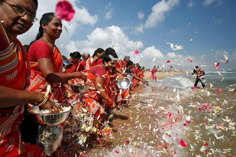 Women scatter flower petals in the waters of the Bay of Bengal during a prayer ceremony for the victims of the 2004 tsunami on the 15th anniversary of the disaster, in Chennai
