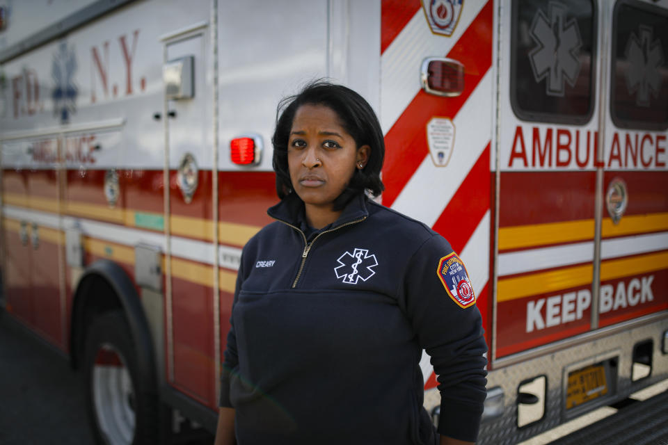 In this April 7, 2020, photo, Virginia Creary, a 911 dispatcher, stands for a portrait outside her station house, in the Bronx borough of New York. The new normal for New York City's emergency workers has come down to this: 911 operators bracing each day for a deluge of calls from a panicked public, dispatchers scrambling to respond and ambulance workers following a "viral pandemic triage" protocol with life-or-death consequences. (AP Photo/John Minchillo)