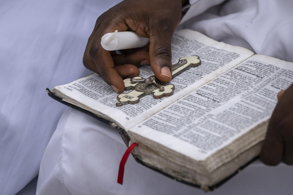 A member of the congregation holds a cross and Bible during a church service in which they prayed for the country ahead of elections and against the forces of evil, at the Celestial Church of Christ Olowu Cathedral on Lagos Island in Nigeria Friday, Feb. 24, 2023. Nigerian voters are heading to the polls Saturday to select a new president following the second and final term of incumbent President Muhammadu Buhari. (AP Photo/Ben Curtis)