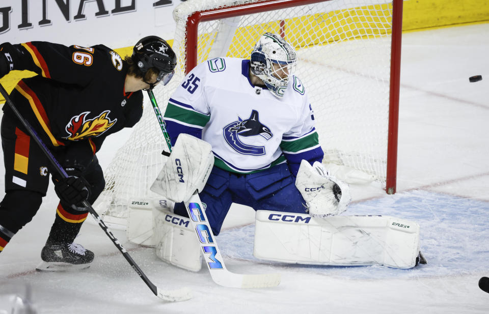 Vancouver Canucks goalie Thatcher Demko, right, blocks the net as Calgary Flames forward Martin Pospisil deflects the puck wide during the first period of an NHL hockey game, Saturday, Dec. 2, 2023 in Calgary, Alberta. (Jeff McIntosh/The Canadian Press via AP)