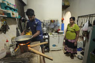 Miraj Madusanka, left, helps his mother Sriyani, light a firewood hearth at their house in Colombo, Sri Lanka, June 10, 2022. Madushanka, a 27-year-old accountant, studied in Japan and hoped to work there. He moved back home in 2018 after his father died, to look after his mother and sister. Madushanka finished his studies and found a job in tourism, but lost it in the shadow of 2019 terror attacks that rattled the country and its economy. The next job evaporated during the pandemic. He's now working for a management company, his fourth job in four years. But even with a reliable paycheck, he can barely manage to support his family. (AP Photo/Eranga Jayawardena)