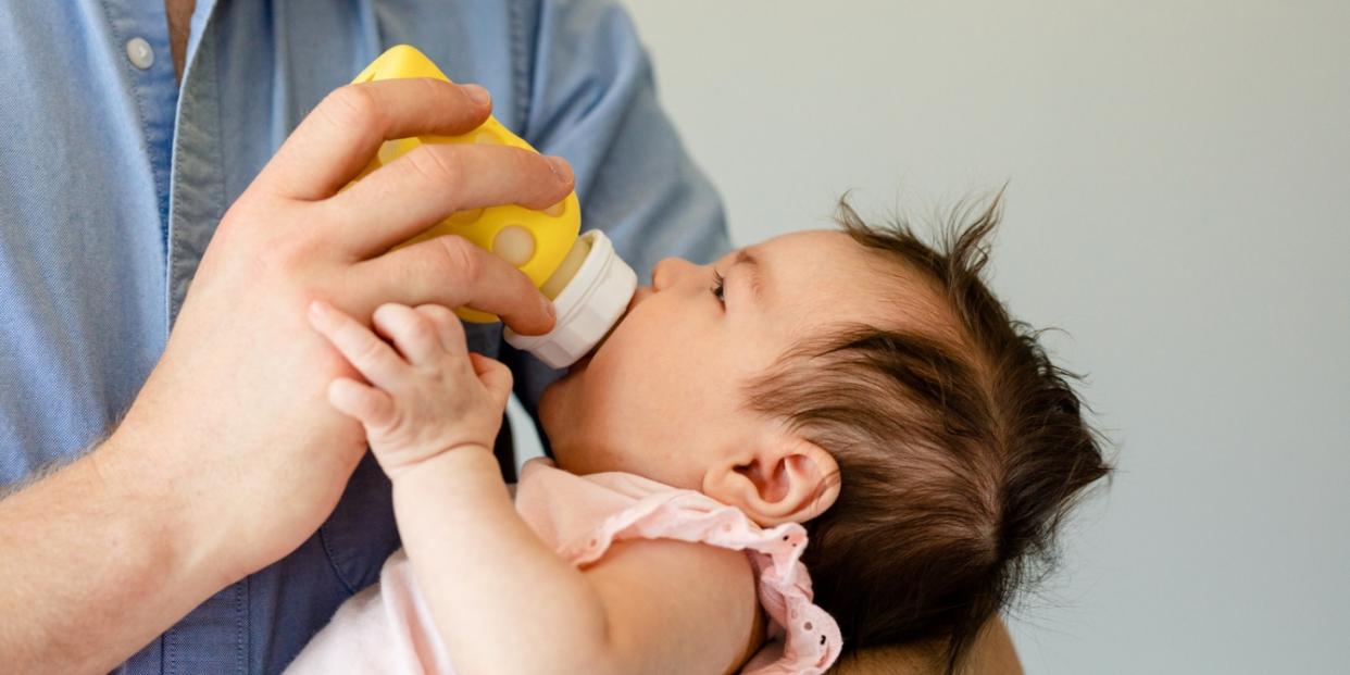 parent feeding baby with bottle formula industry