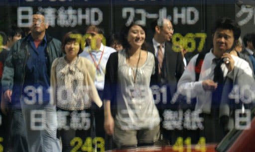 This file photo shows pedestrians reflected on a share prices board in Tokyo, in 2011. Japan's unemployment rate improved slightly to 4.3 percent in June from 4.4 percent in May, the internal affairs ministry said on Tuesday