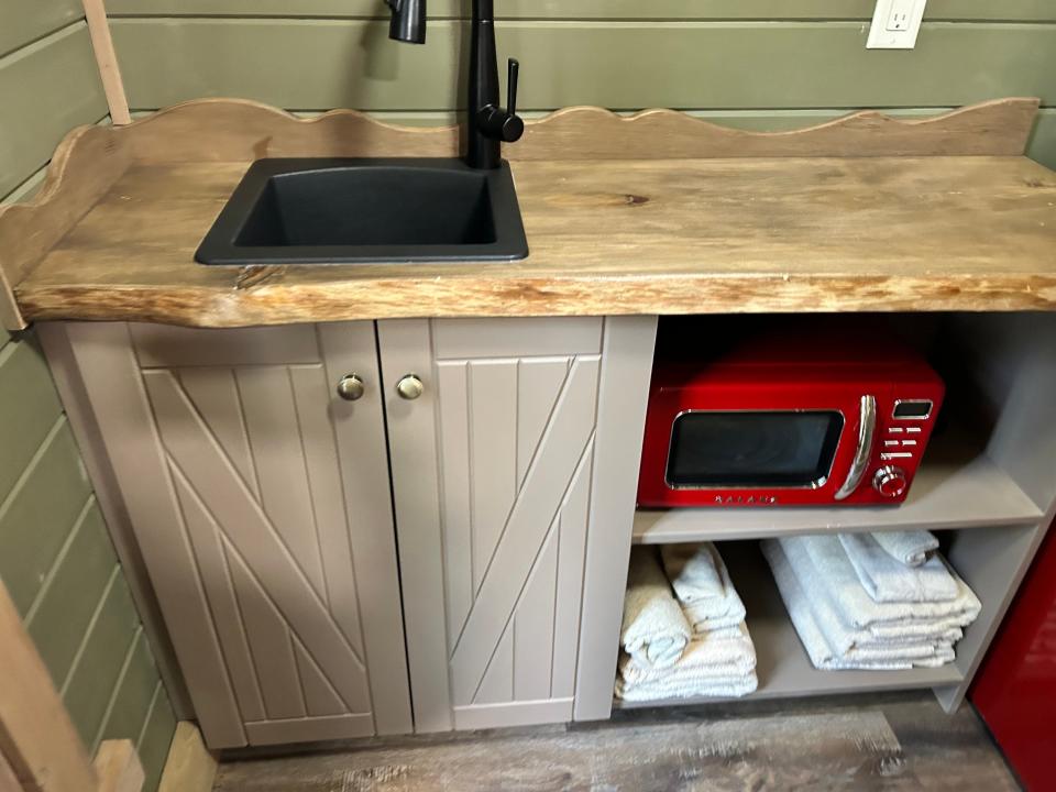 close up of kitchenette with red microwave, towels