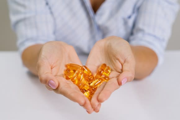 A person holds fish oil pills in her hand.