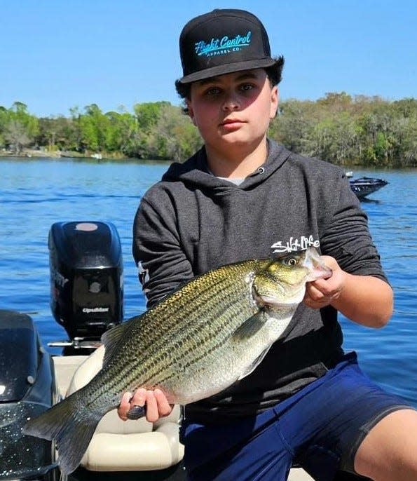 Raymond Cardona with a striped bass pulled from the St. Johns River.