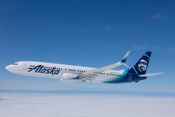 Jet aircraft bearing Alaska brand and logo in flight on a clear day.