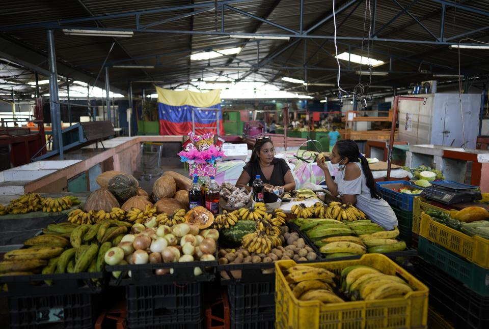 Produce vendors wait for customers at a market in Caracas, Venezuela, Friday, Oct 1, 2021. A new currency with six fewer zeros debuts today in Venezuela, whose currency has been made nearly worthless by years of the world's worst inflation. The new currency tops out at 100 bolivars, a little less than $25 until inflation starts to eat away at that as well. (AP Photo/Ariana Cubillos)