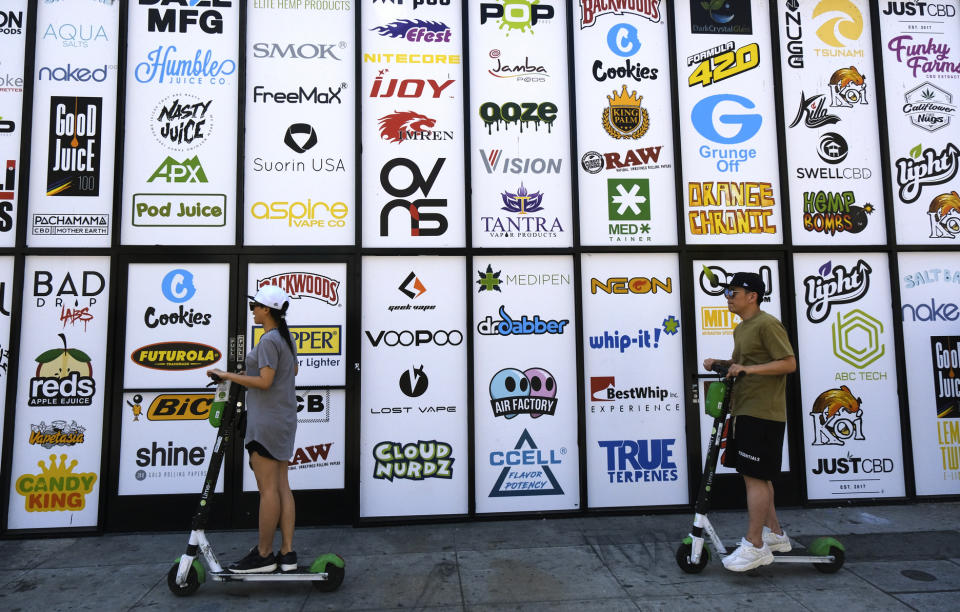 This Wednesday, Aug. 28, 2019, photo shows advertising logos for different cannabis brands posted on the side of a shop on a street lined with wholesale cannabis vape shops in downtown Los Angeles. A short walk from police headquarters in the heart of downtown, a cluster of bustling shops are openly selling packaging and hardware that can be used to produce counterfeit, and potentially dangerous, marijuana vapes that have infected California's cannabis market and possibly sickened dozens of people. (AP Photo/Richard Vogel)