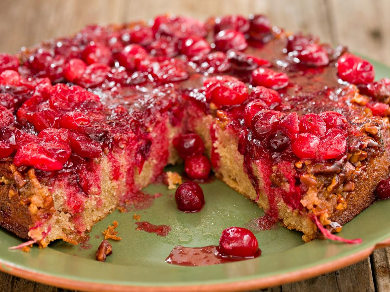 A high angle close up shot of a holiday upside down cranberry cake on a green plate.