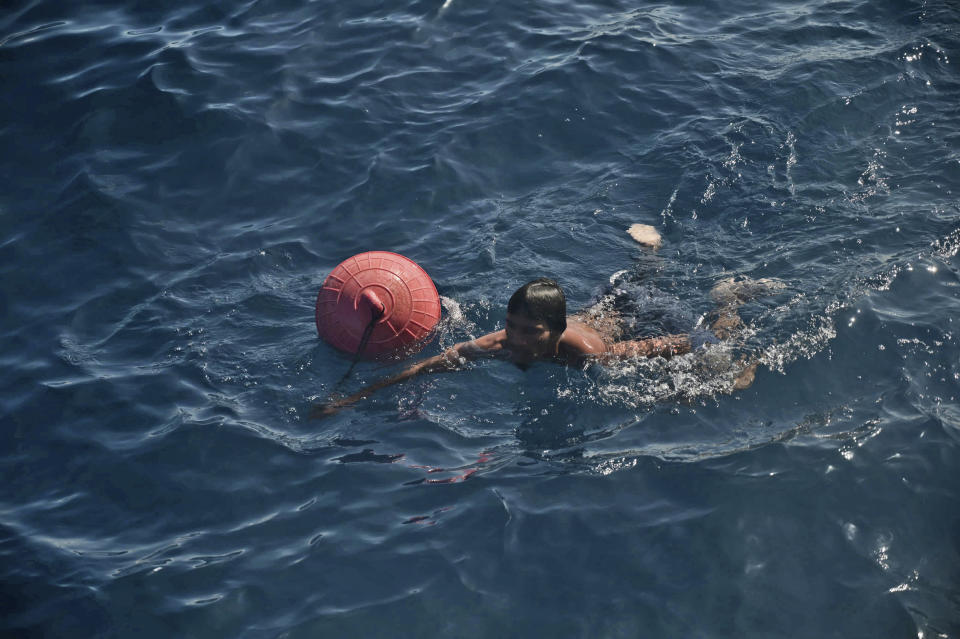 A Rohingya refugee holds a floatation device as he swims towards a rescue boat while being rescued from his capsized boat in the waters off West Aceh, Indonesia, Thursday, March 21, 2024. An Indonesian search and rescue ship located a capsized wooden boat that had been carrying dozens of Rohingya Muslim refugees, and began pulling survivors who had been standing on its hull to safety Thursday. (AP Photo/Reza Saifullah)