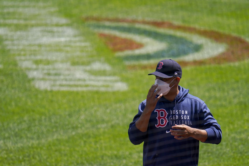 Boston Red Sox manager Alex Cora sends signs to third base coach third base coach Carlos Febles during the first inning of a baseball game against the Baltimore Orioles, Sunday, April 11, 2021, in Baltimore. (AP Photo/Julio Cortez)