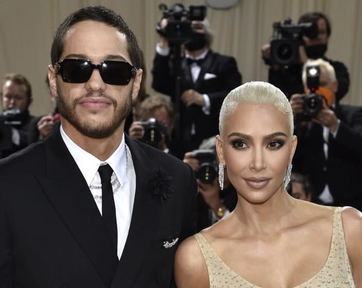 A man in sunglasses and a woman with platinum hair arrive at a gala together