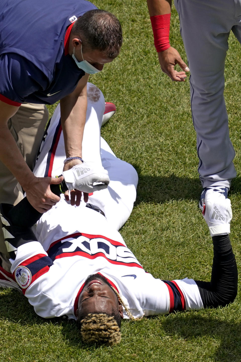 Chicago White Sox's Luis Robert, bottom, is checked by a team trainer after an injury during the first inning of a baseball game against the Cleveland Indians in Chicago, Sunday, May 2, 2021. (AP Photo/Nam Y. Huh)